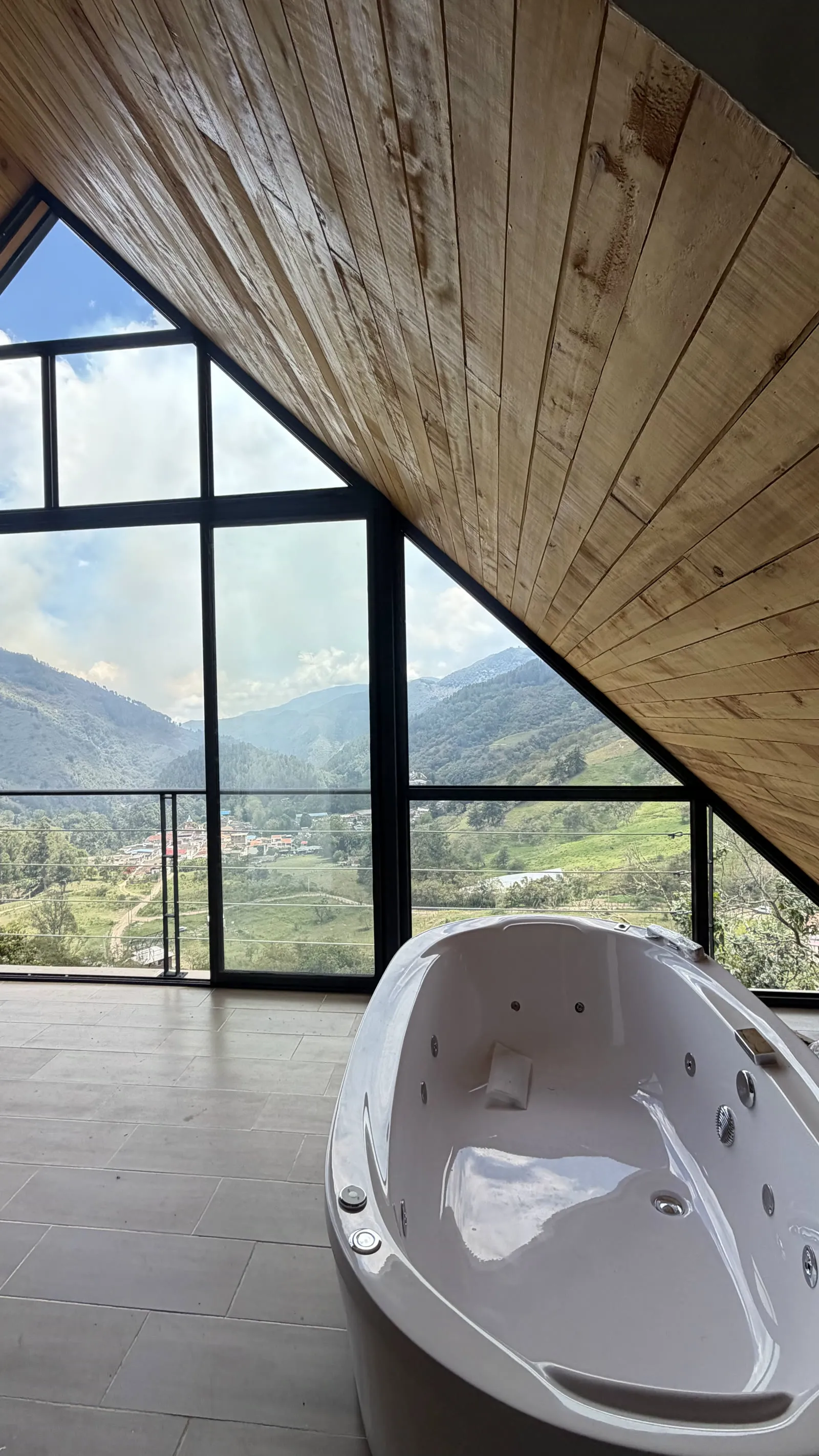 Interior de una cabaña con jacuzzi y ventanal a la montaña